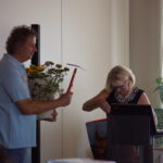 Mann übergibt der Frau einen Strauß Blumen und eine Hacke