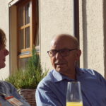 Zwei Personen auf einer Terrasse die sich Unterhalten
